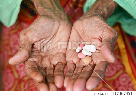 close up of pills and capsule on senior women's hand 117367451
