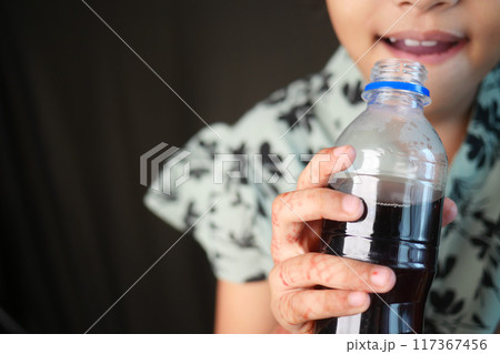 little girl holding a bottle of soft drinks  117367456