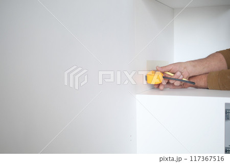 Man measuring wall with a tape measure  117367516