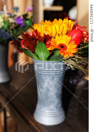 Vibrant Autumn Flower Bouquet in Rustic Metal Vase on wooden table at countryside village farm rustical house. Bright floral seasonal composition in bucket. Nature farmyard blossom arrangement Vibrant Autumn Flower Bouquet in Rustic Metal Vase on wooden table at countryside village farm rustical house. Bright floral seasonal composition in bucket. Nature farmyard blossom arrangement 117368949