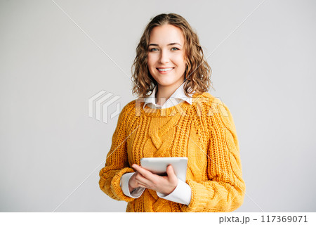 Smiling Young Professional with Digital Tablet. A cheerful businesswoman or student, holding a Smiling Young Professional with Digital Tablet. A cheerful businesswoman or student, holding a 117369071