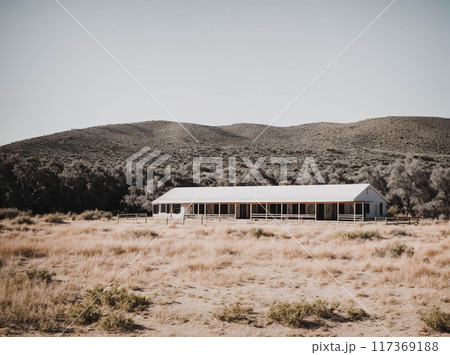 A large, old-fashioned building sits in a field with a mountain in the background 117369188