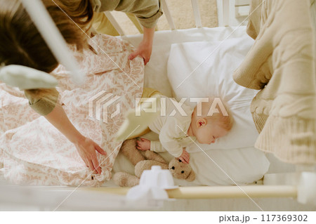 Top view of nurturing moment with baby sleeping peacefully in crib surrounded by soft blankets and stuffed animals Top view of nurturing moment with baby sleeping peacefully in crib surrounded by soft blankets and stuffed animals 117369302