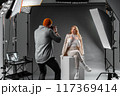 Explore the behindthescenes of a fashion photoshoot in a studio with a model and photographer 117369414