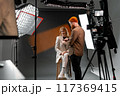 Professional Studio Photoshoot with Female Model and Photographer Adjusting Lighting 117369415
