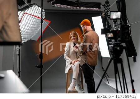 Professional Studio Photoshoot with Female Model and Photographer Adjusting Lighting 117369415