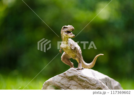 Child playing with dinosaur toy in sunny garden 117369602