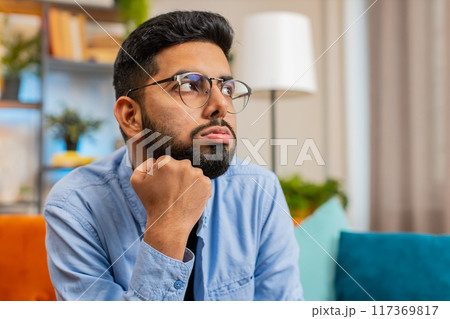 Thoughtful Indian man suffers from unfair situation break up depressed feeling bad annoyed burnout 117369817