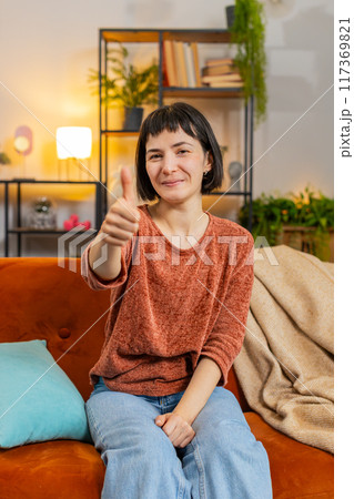 Excited Caucasian woman looking approvingly at camera showing thumbs up, like sign positive feedback 117369821