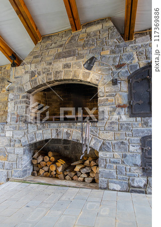 Stone restaurant barbecue firewood, open brick oven cooking food dishes on fire indoors in backyard 117369886