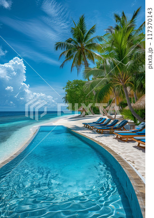 A gorgeous tropical beach resort with a swimming pool and sun loungers on a white sandy beach. Blue sky and palm trees Beautiful scenery of a luxurious summer vacation. 117370143