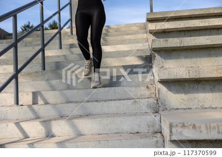Woman in black sportswear going downwards on the steps 117370599