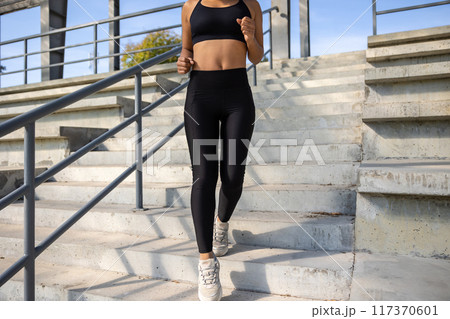 Woman in black sportswear going downwards on the steps 117370601