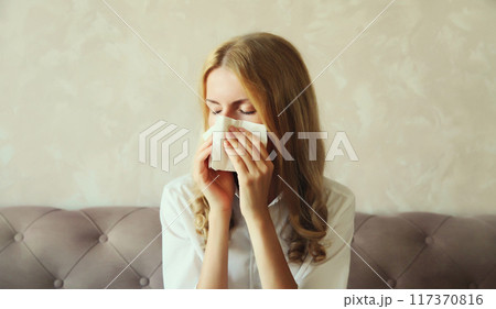 Sick exhausted young woman sneezing blow nose using tissue, unhealthy suffering girl feels unwell Sick exhausted young woman sneezing blow nose using tissue, unhealthy suffering girl feels unwell 117370816