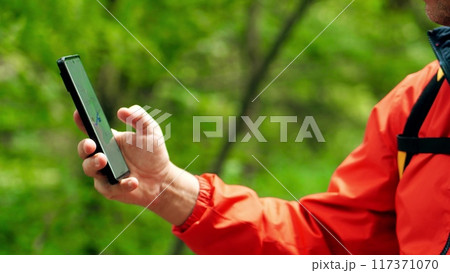 Man uses his smartphone with a navigation map app in the woods 117371070