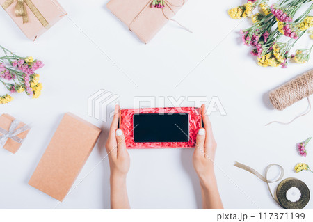 A woman is holding a cell phone in a red box 117371199