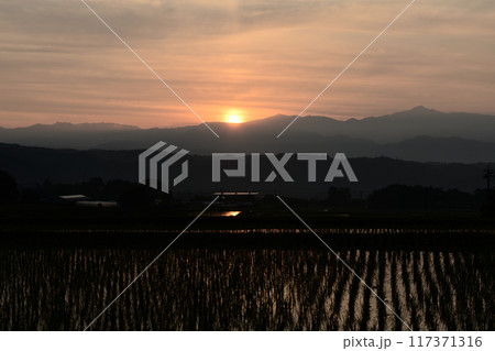 北杜市白州町から見る奥秩父の山から昇る朝日が空や田んぼを朱に染める 117371316