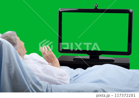Pale Senior Woman Communicates via Green Screen Monitor from Hospital Bed, Engaging in Telemedicine or Virtual Family Visit. Pale Senior Woman Communicates via Green Screen Monitor from Hospital Bed, Engaging in Telemedicine or Virtual Family Visit. 117372281