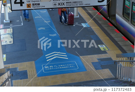 駅の跨線橋階段を下りたホーム上、一か所への滞留を防止するための表示 117372483