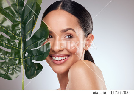 Happiness is having natural beauty. Studio shot of a beautiful young woman posing with a leaf against a grey background. Happiness is having natural beauty. Studio shot of a beautiful young woman posing with a leaf against a grey background. 117372882