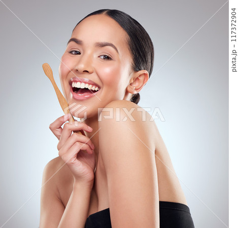 This brush has been sustainably sourced. Studio portrait of a beautiful young woman brushing her teeth against a grey background. 117372904