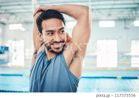 Happy, man and stretching at a swimming pool for training, cardio and exercise, indoor and flexible. Athlete, smile and swimmer stretch for workout, swim and fitness routine, warm up and preparation 117373556
