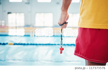 Hands, lifeguard and whistle by swimming pool for water safety, security or ready for rescue indoors. Hand of expert swimmer holding signal tool for warning, safe swim or responsibility for awareness 117373576