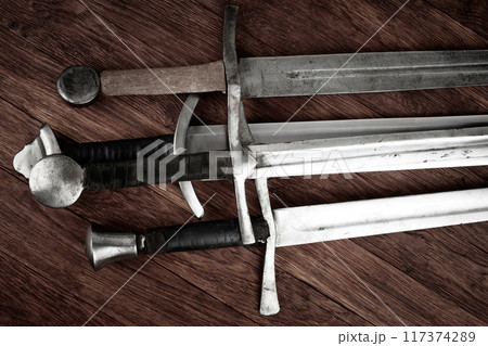 Medieval swords on wooden background. Medieval swords on wooden background. 117374289