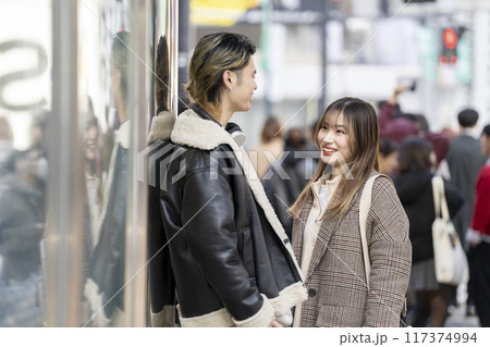 街角で笑顔で会話をする若い男女 117374994