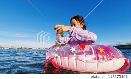 真夏の海水浴場で浮き輪を使って水遊びする小学生の女の子の様子 真夏の海水浴場で浮き輪を使って水遊びする小学生の女の子の様子 117375308