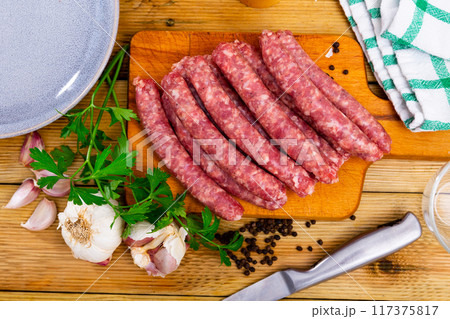 Catalan raw pork sausage longaniza ready for grilling on wooden board 117375817