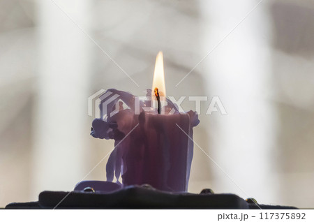 Burning candle in the shape of a unicorn on a light background 117375892