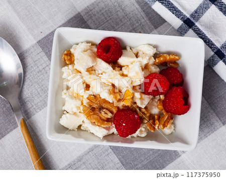Farm cottage cheese filled with large amount of honey with walnut and raspberry. 117375950