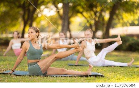 Yoga lesson visitors girls perform eka padahastasana salamba navasana in park 117376004