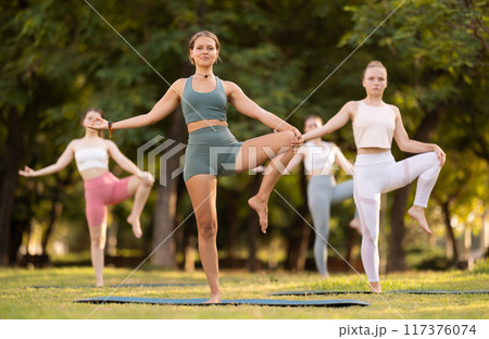 Focused young female yoga practitioner performing Garudasana in garden 117376074