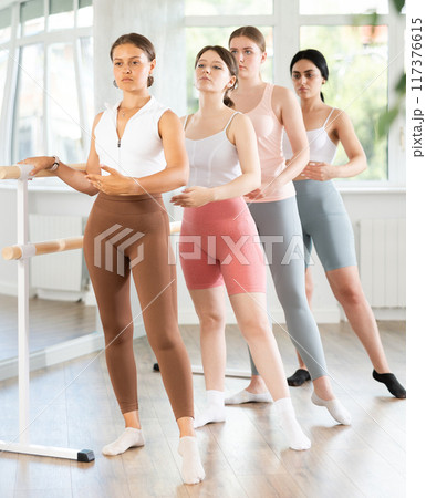 Young girl practicing battement tendu at barre in ballet class 117376615