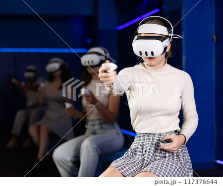 Young woman immersed in virtual reality game in gaming center Young woman immersed in virtual reality game in gaming center 117376644