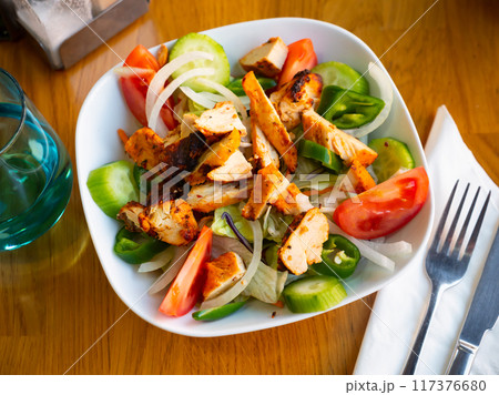 Chicken salad with fresh vegetables on table in restaurant 117376680