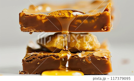 Close-up of rich chocolate brownies layered with caramel, showcasing a gooey center and topped with chocolate pieces, perfect for a decadent treat.. Close-up of rich chocolate brownies layered with caramel, showcasing a gooey center and topped with chocolate pieces, perfect for a decadent treat.. 117379095