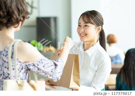 お客様に商品を渡す若い女性 117379817