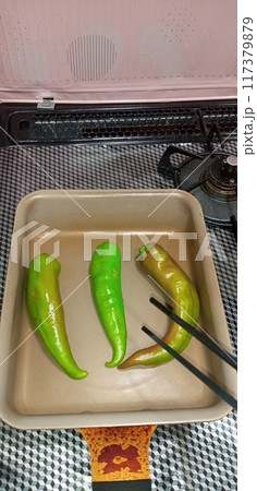 焼いた万願寺唐辛子を菜箸でひっくり返そうとしている 117379879