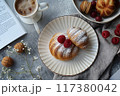Gourmet breakfast scene featuring a beautifully crafted pastry, a cup of coffee, fresh berries, and a cinnamon drink.. 117380042