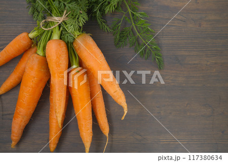 Fresh carrots with green leafy tops on rustic wooden table Fresh carrots with green leafy tops on rustic wooden table 117380634