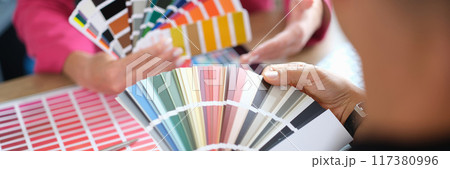 Woman designer holding fan of colourful paper samples in hand. 117380996
