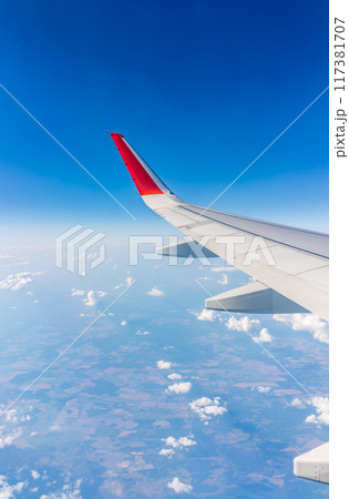 View from the airplane window at a beautiful cloudy sky and the airplane wing 117381707