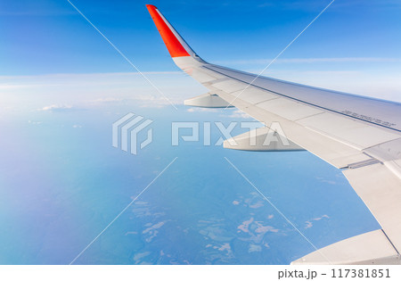 View from the airplane window at a beautiful cloudy sky and the airplane wing 117381851