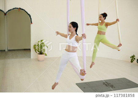 Practicing Aerial Yoga on Suspended Ribbons in Studio 117381858
