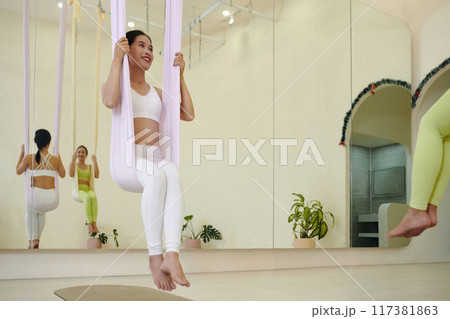 Practicing Aerial Yoga in Modern Studio Space Practicing Aerial Yoga in Modern Studio Space 117381863