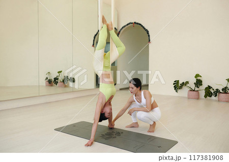 Guiding Yoga Aerial Pose with Supportive Instructor 117381908