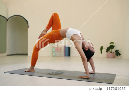 Practicing Advanced Yoga Pose in Modern Studio Setting 117381985